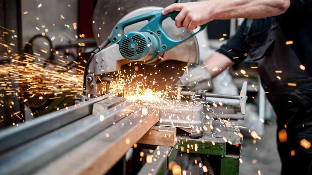 Person cutting metal with a circular miter saw.