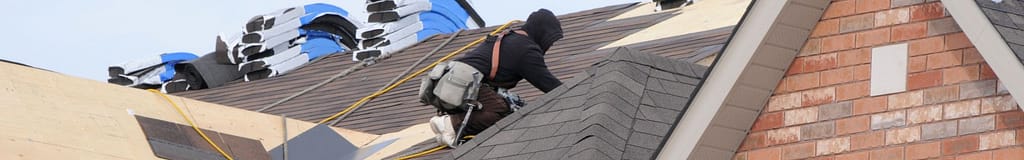 Roofer working on a roof with a safety harness