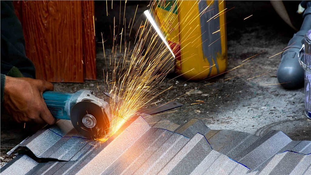 Person using angle grinder to cut metal roofing
