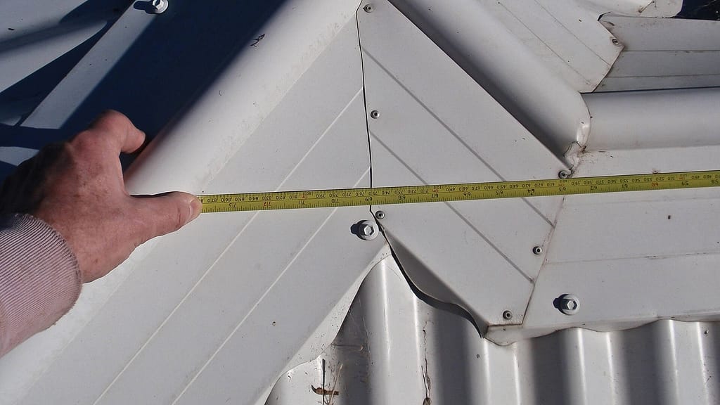 Person measuring roof using tape measure