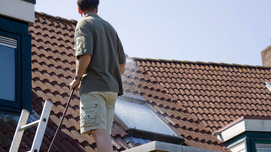 Person spraying water on roof using a hose