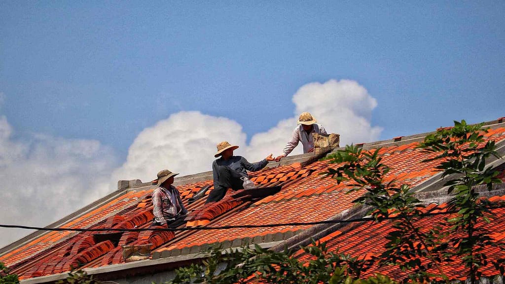 3 people working on a tile roof
