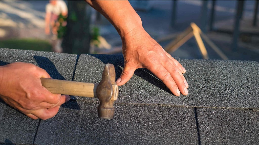 Person fixing asphalt roof shingle