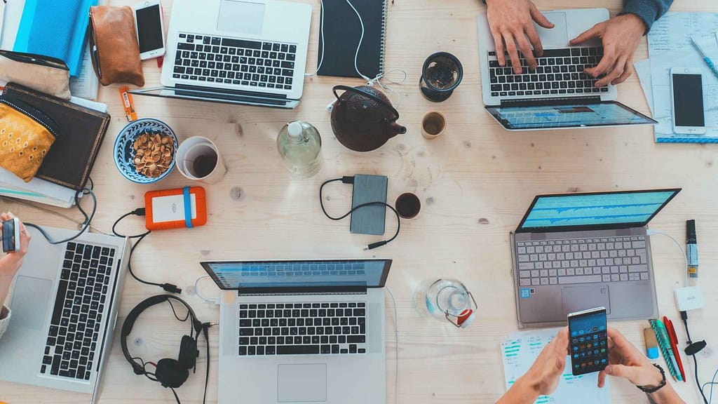 Dev team working on a table with many laptops