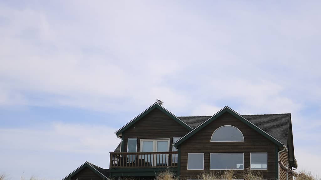 brown house and gray roof over blue sky inspected by Kansas roofer