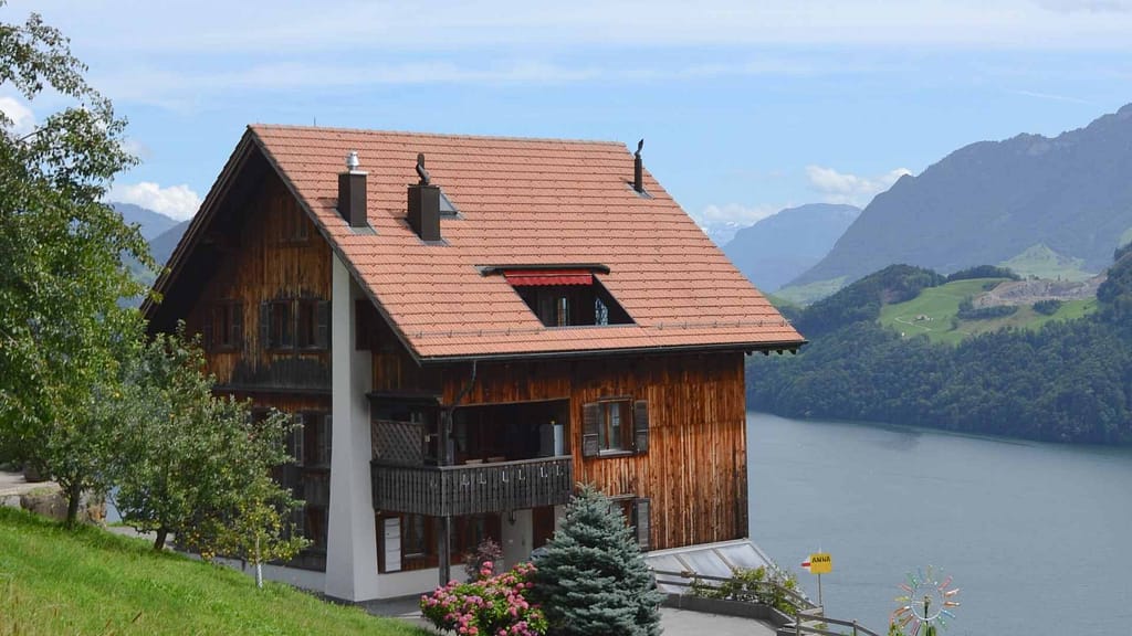 house with orange roof beside water and mountain view inspected by Hawaii roofing contractor