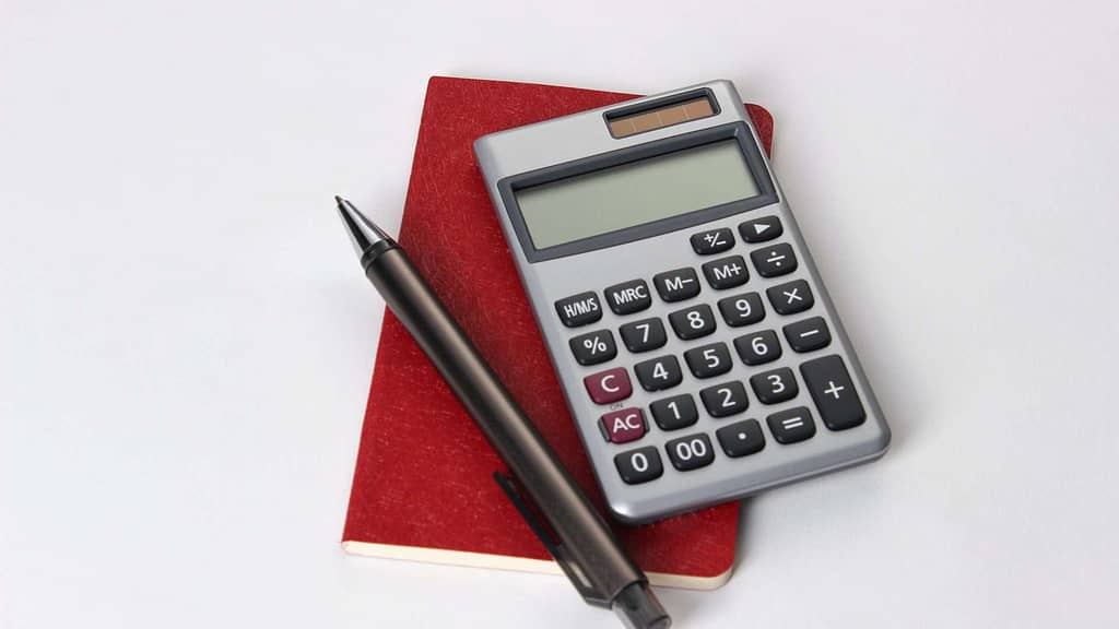 red notebook pen and calculator for Iowa roof replacement cost planning