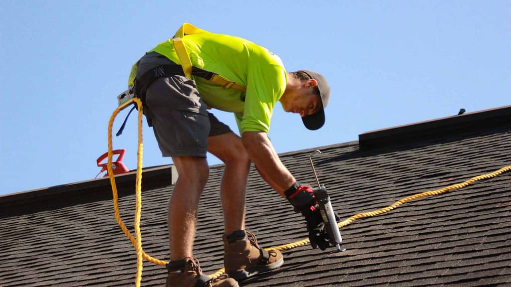 skilled Alabama roofer in neon green shirt during installation