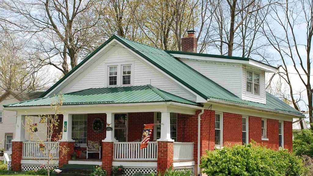 white and orange home with green roofing inspected by a skilled Maine roofer