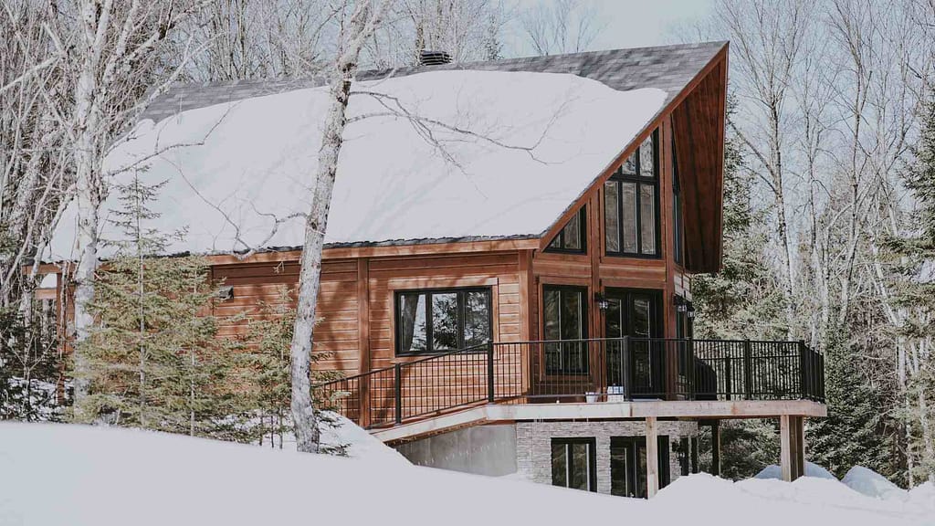 home and forest trees covered in snow affects over all Alaska new roof cost