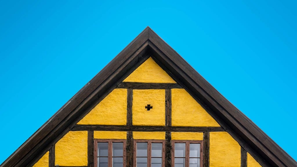 yellow and brown house with plus sign checked by a skilled Kansas roofing contractor