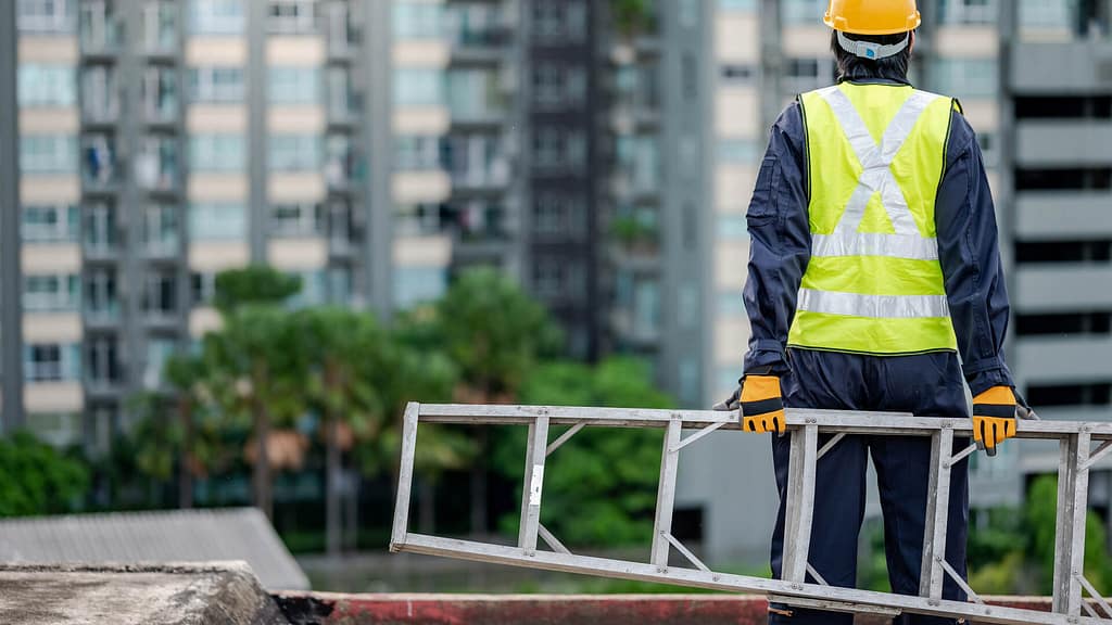 Construction man carrying a ladder