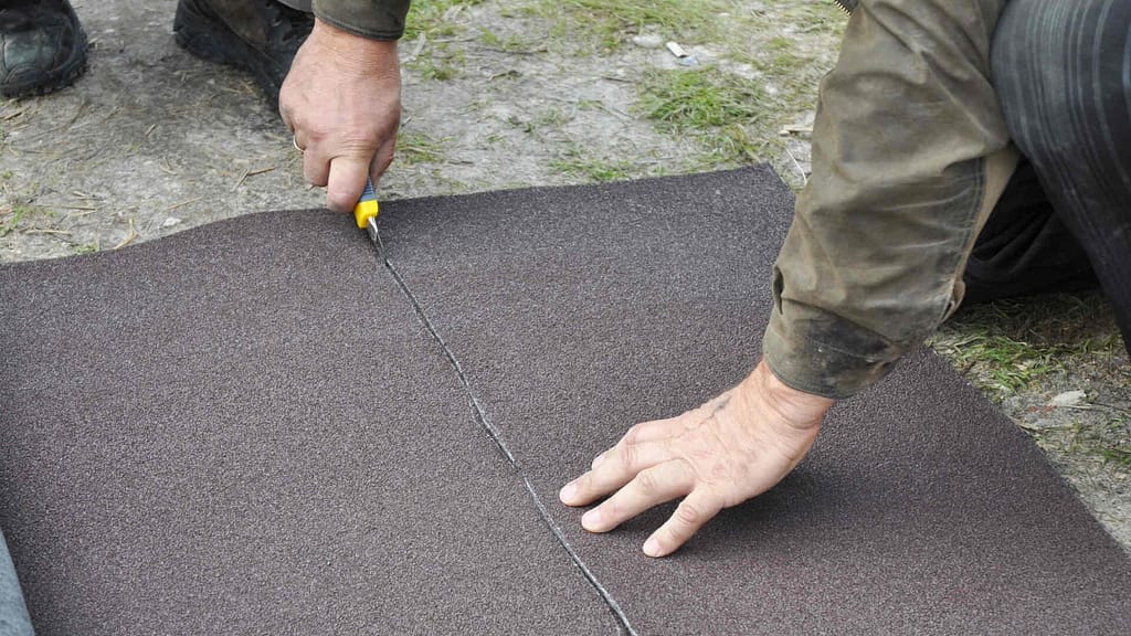 person using a cutter to cut a saturated felt roofing underlayment