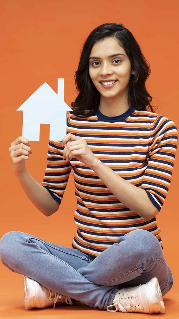 Person sitting crosslegged holding a home with roof icon
