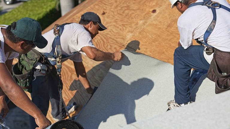 Roofers installing a membrane on a roof