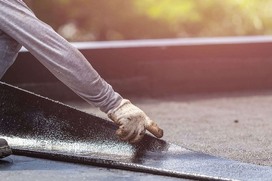 man laying membrane on a flat roof