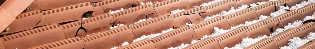 Close up of broken clay tiles from hail damage on a roof