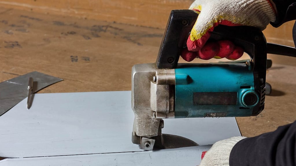 Person using nibbler to cut a metal sheet.