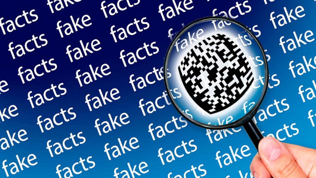 An image of a hand holding a magnifying glass to evaluate fake vs facts