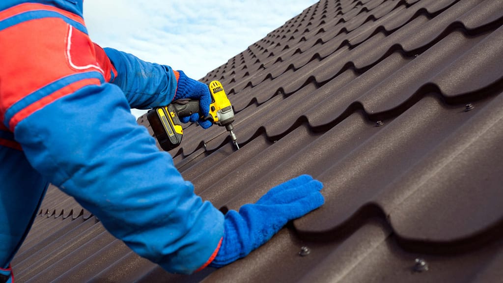 person drilling nails on a metal roof