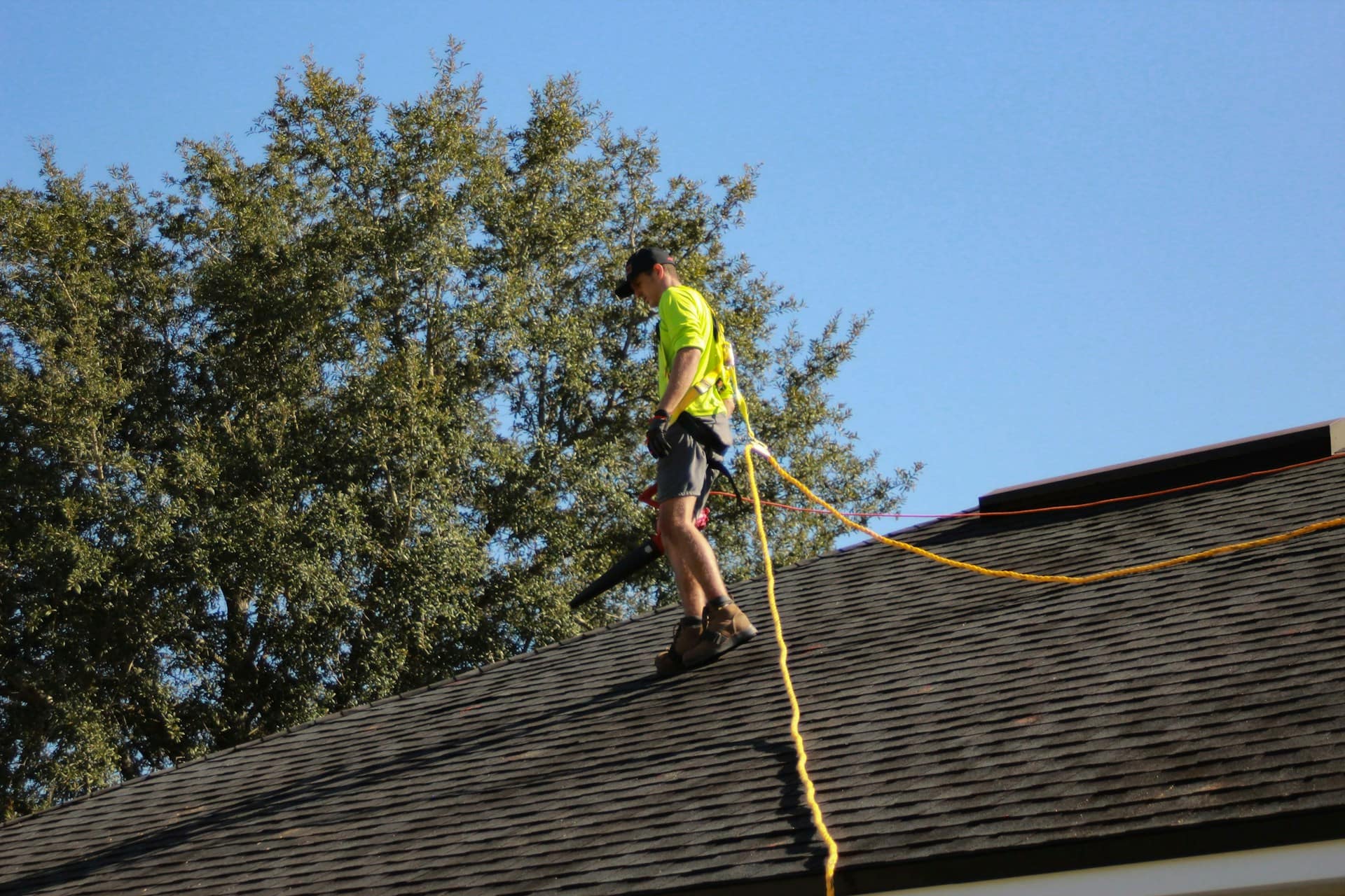 roofer walking on residential roof with safety harness.
