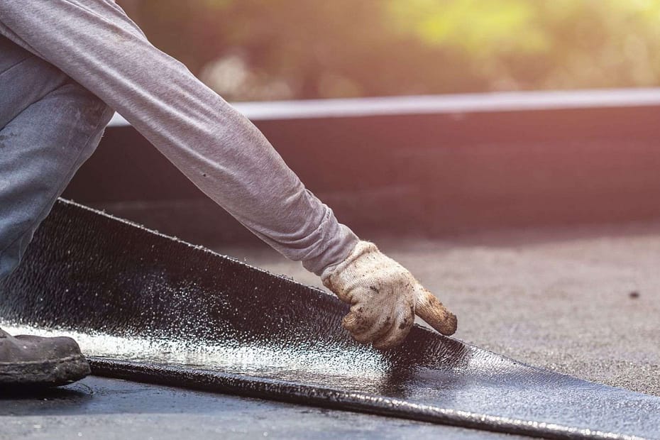 man laying membrane on a flat roof