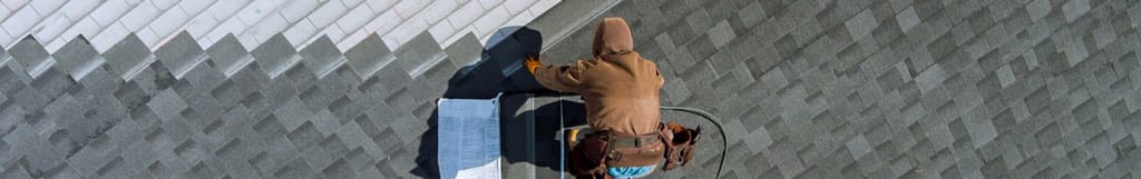 A roofing contractor nailing down asphalt shingles