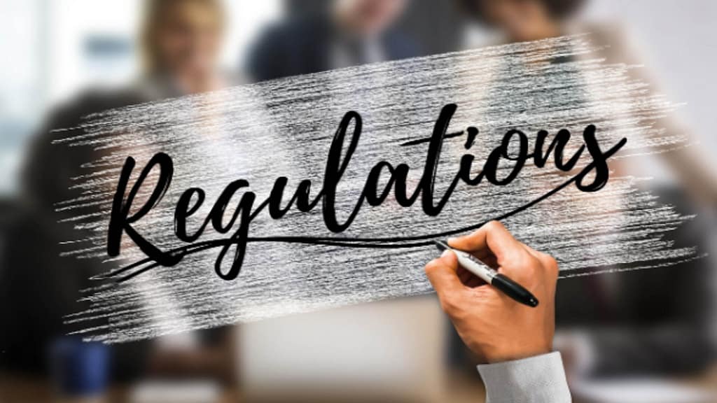 Image of a hand writing the text "Regulations"