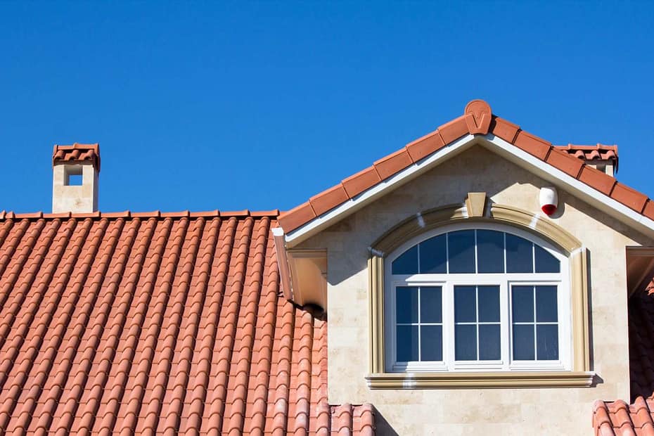 home with a clay tile roof against a bright blue sky
